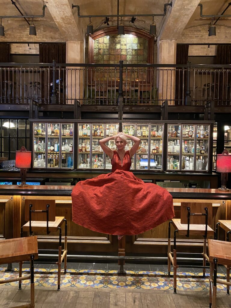 Style beyond age wearing red dress and sitting on a bar