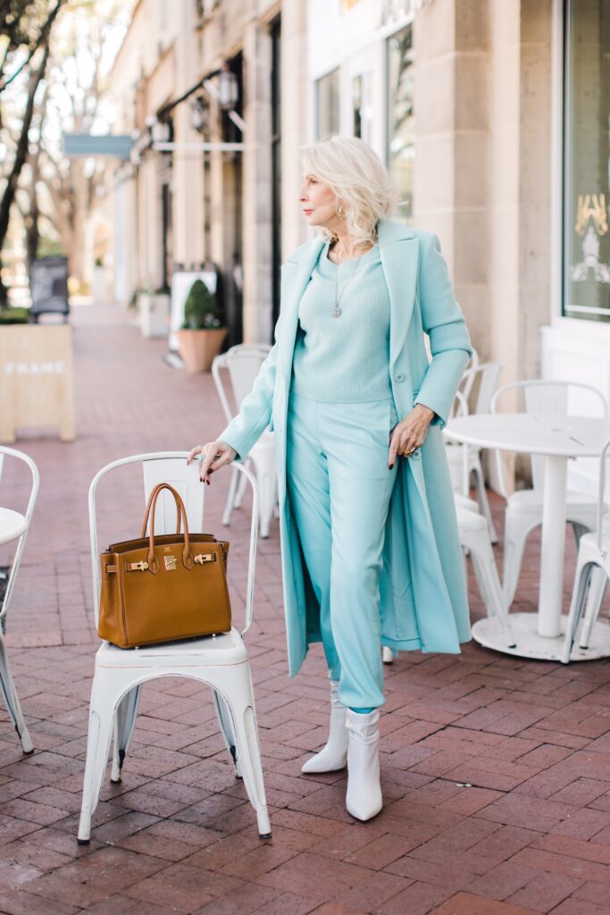 Woman wearing a seafoam overcoat with vegan leather joggers and cashmere sweater for the spring travel  edit with Alice and Olivia