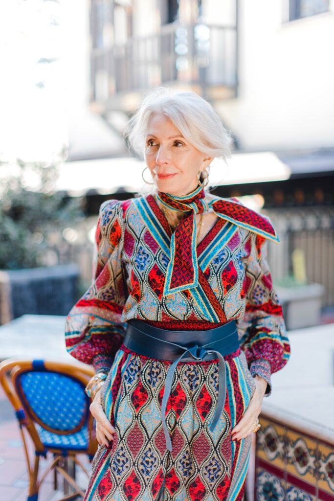 Woman wearing print palazzo pants and top with a leather wrap belt 