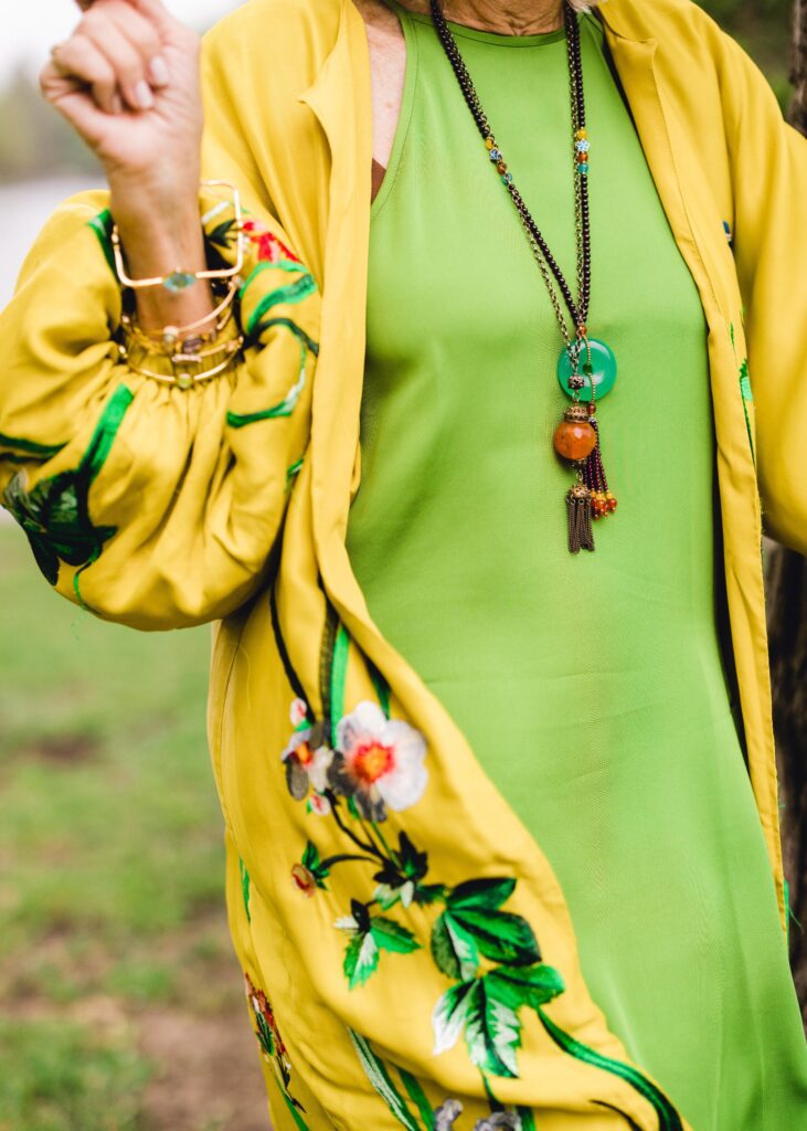 close up of hanging pendants on a green slip dress with yellow kimono