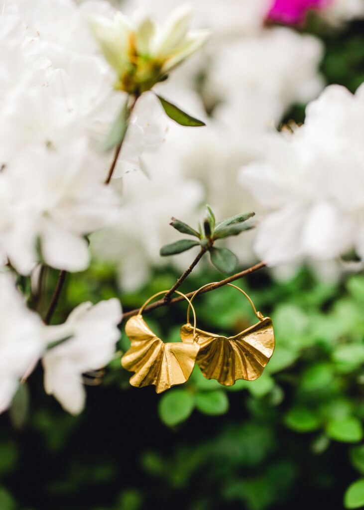 close up of matte gold fanned shaped earrings