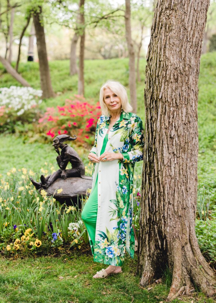 leaning on tree in park wearing green slip dress with white flowered shirt