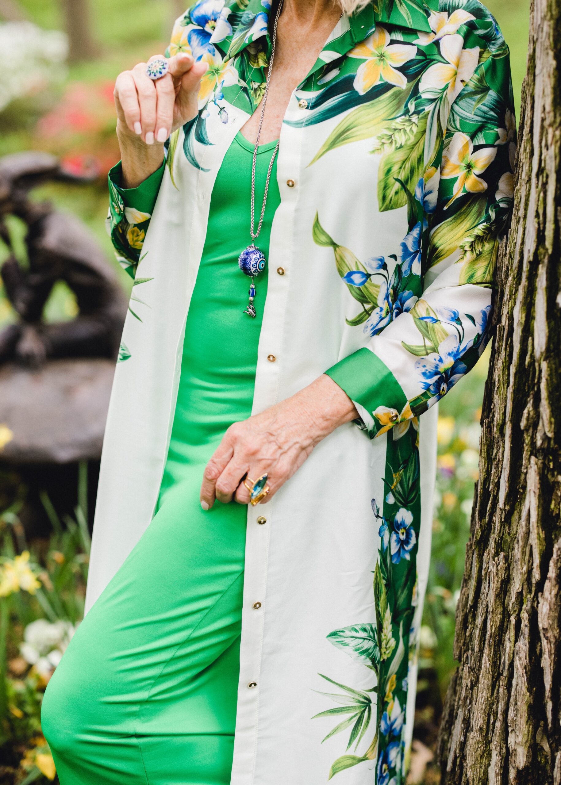 close up of green dress with flowered long shirt and hanging pendant