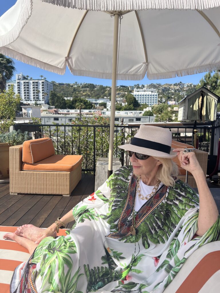 Dallas blogger laying on lounge chair wearing Lotta Stensson kafta, Eric Javits Hat and Ray Ban sunglasses