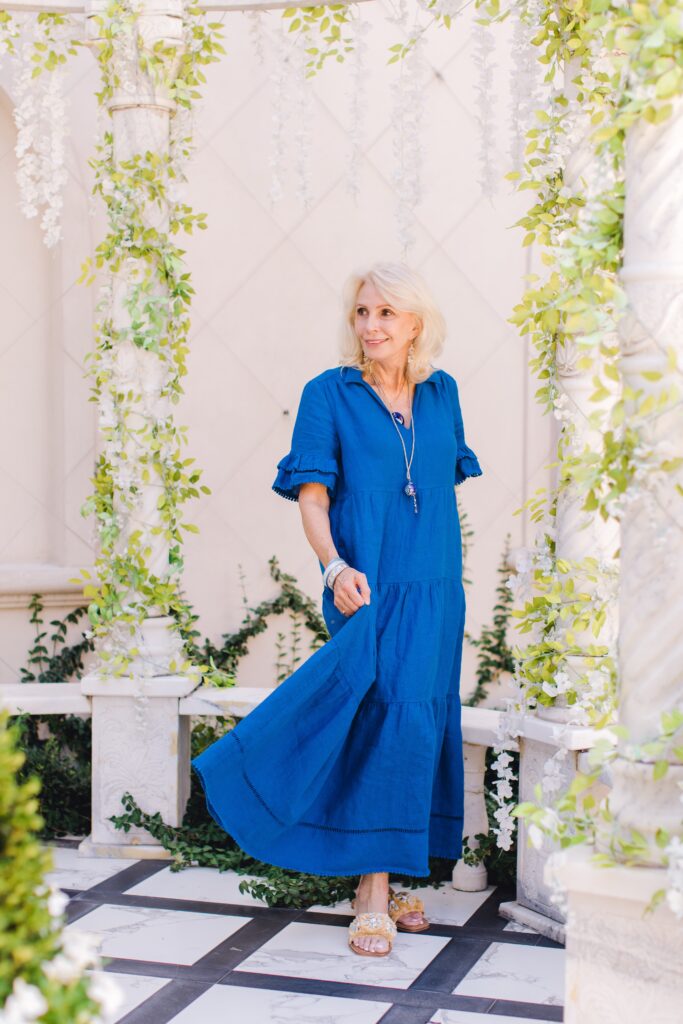 Smiling woman standing in courtyard  holding skirt of blue dress