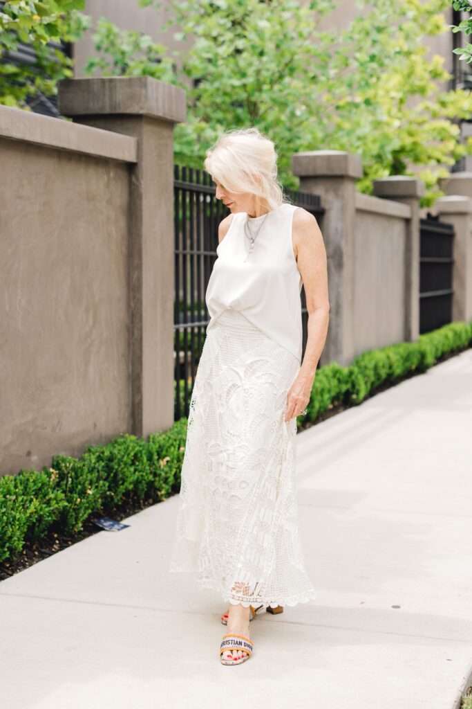 Woman modelling summer neutral silk top and lace skirt