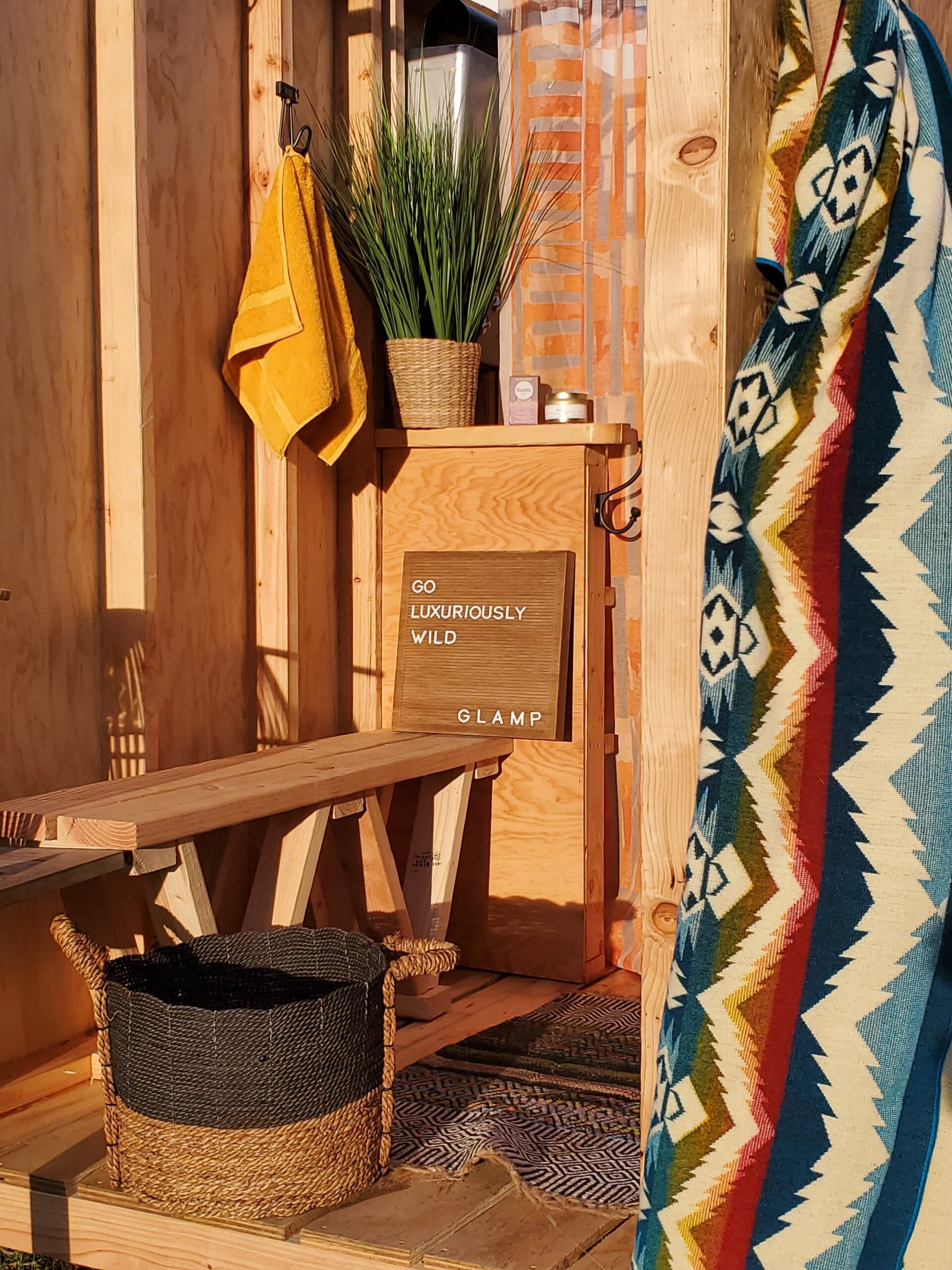 Wooden shower area, with a wooden bench and a multicolored towel hanging from a hook