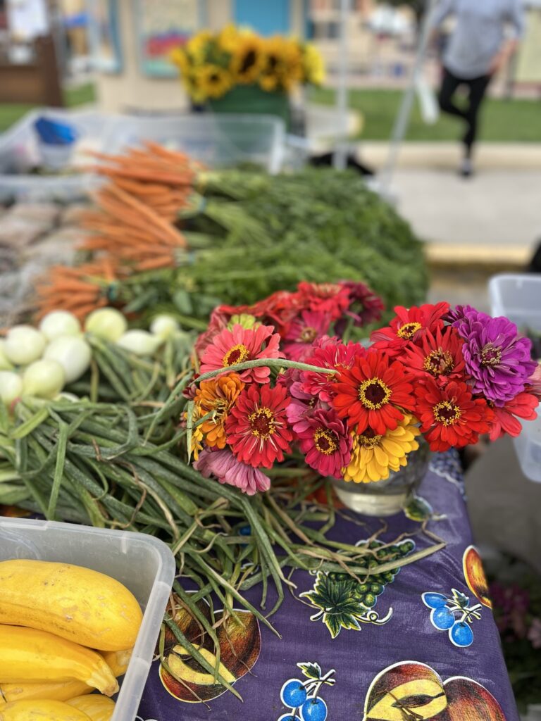 A bushel of flowers and various vegetables on a table