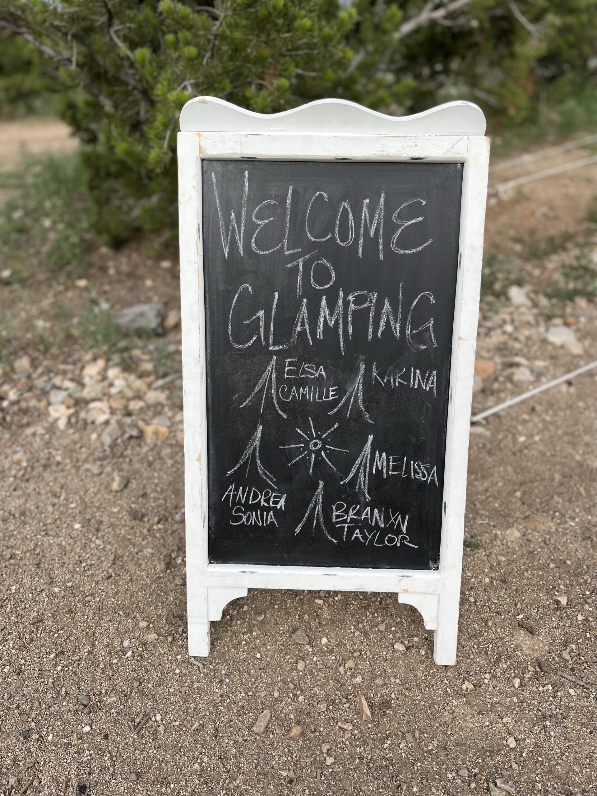 White framed chalkboard sign saying Welcome to Glamping