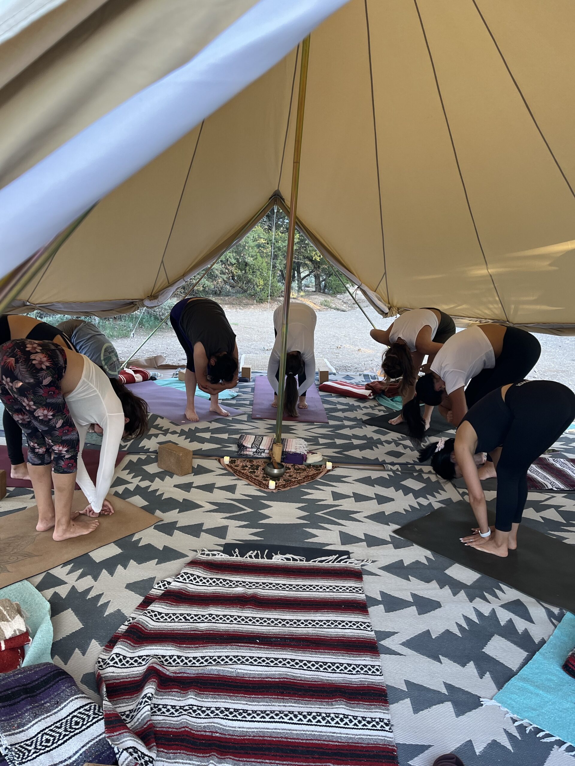 Group of women stretching on yoga mats under large white tent