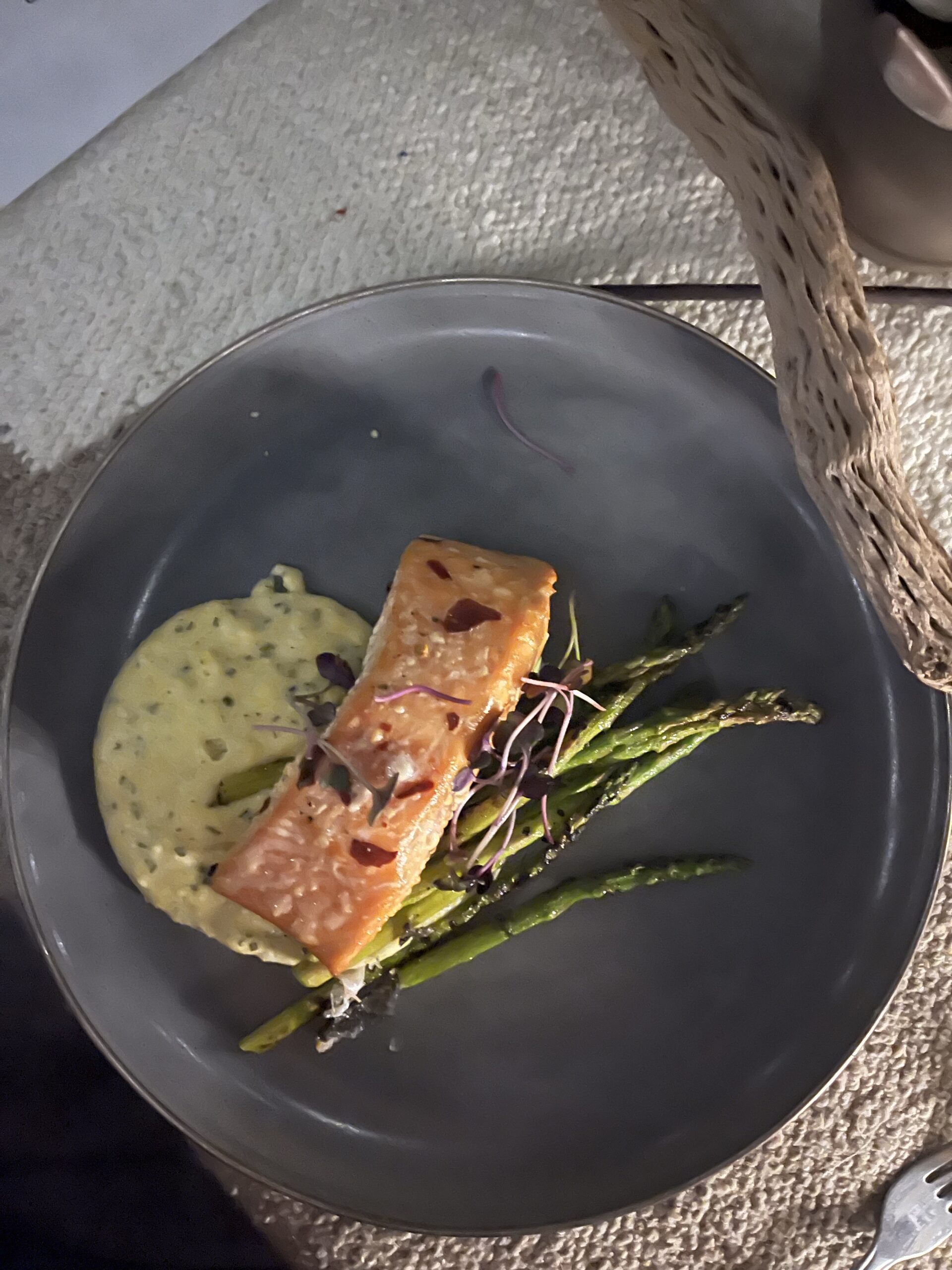 Gray plate with piece of fish and asparagus with white sauce