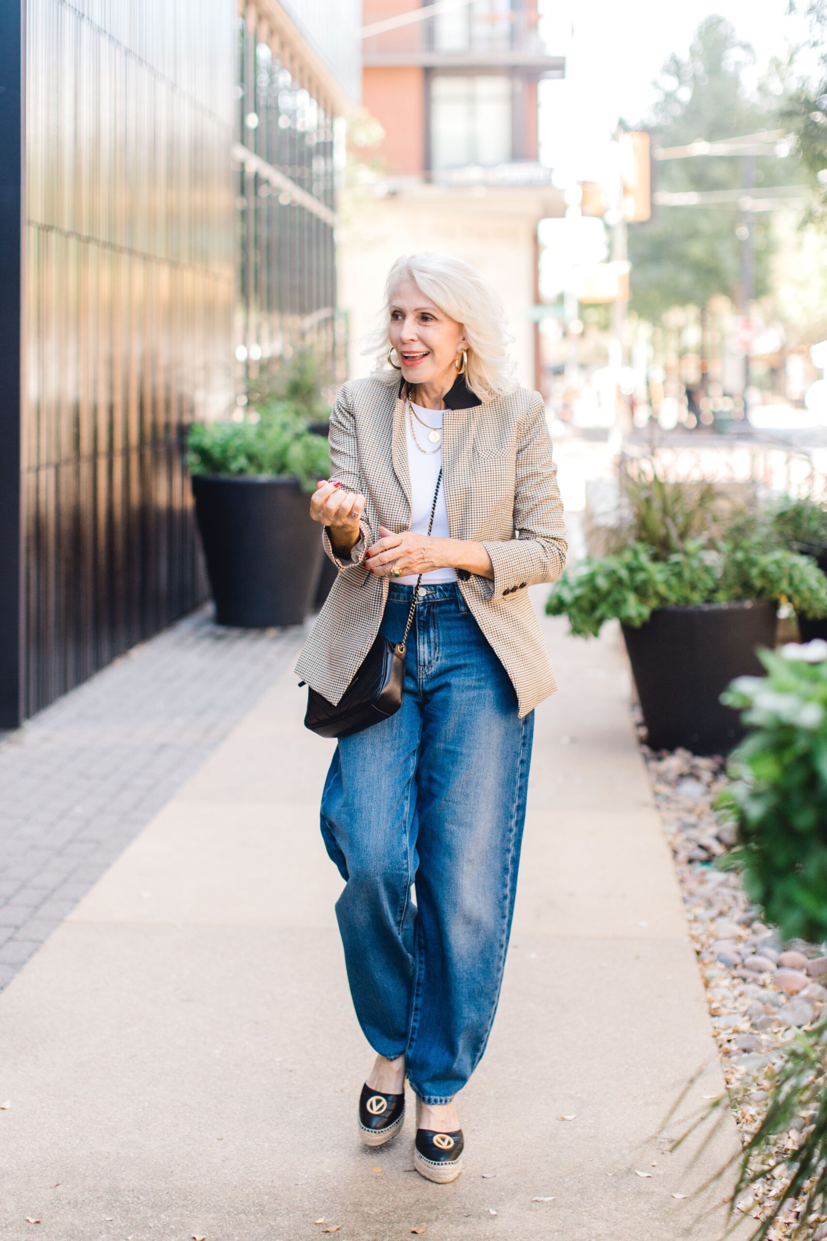 Woman over 60 wearing blazer and wide-legged jeans