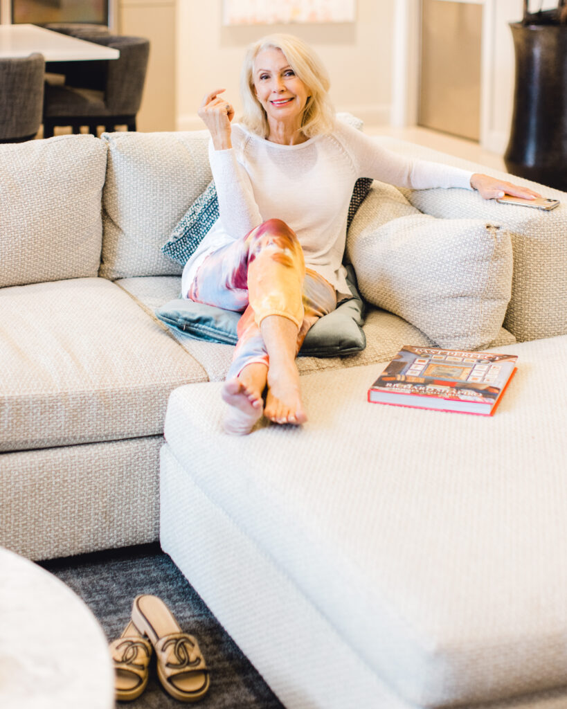 Woman smiling while sitting on couch discussing prenuvo body scans