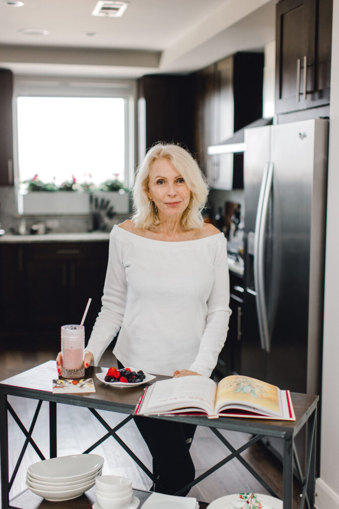 Style beyond age standing at table with smoothie and cookbook