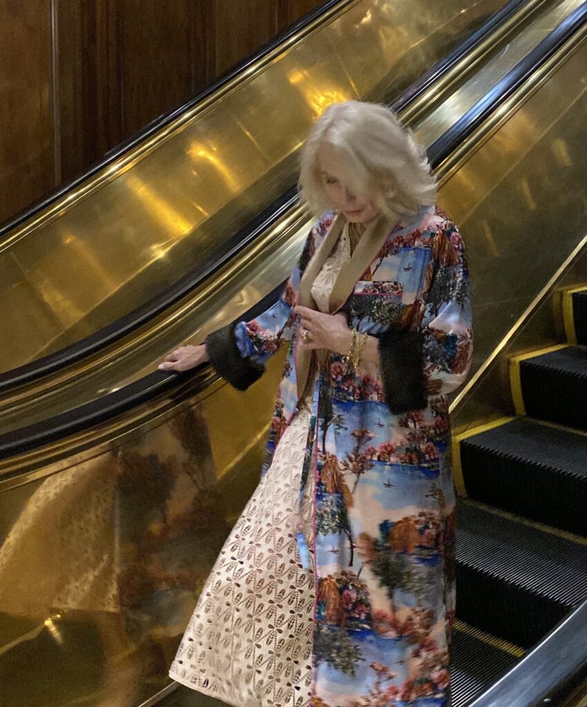 Dallas woman walking down an escalator wearing long coat and dress edit