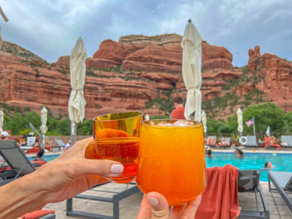 Clinking drinks together by the pool on a girls' trip